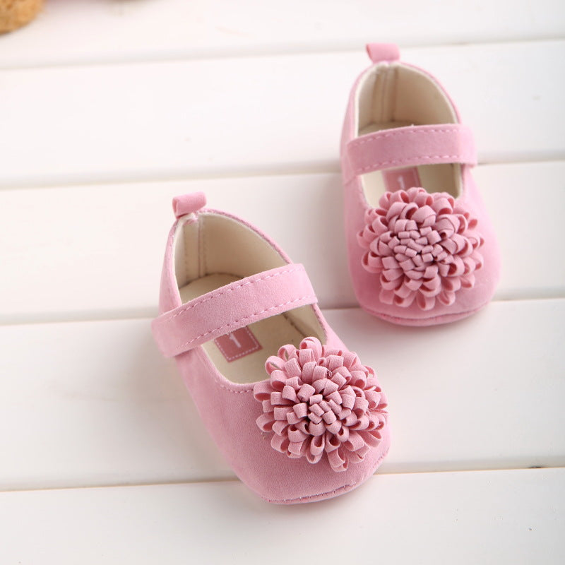 Pink suede baby Mary Jane shoes with a large ruffled flower applique and strap closure.