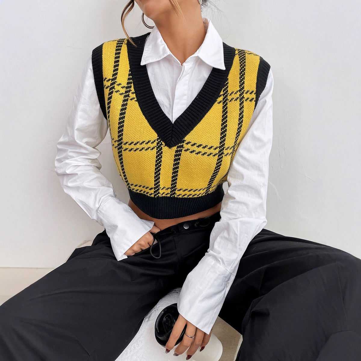 Yellow and black plaid knit V-neck sweater vest worn over a white button-down shirt.