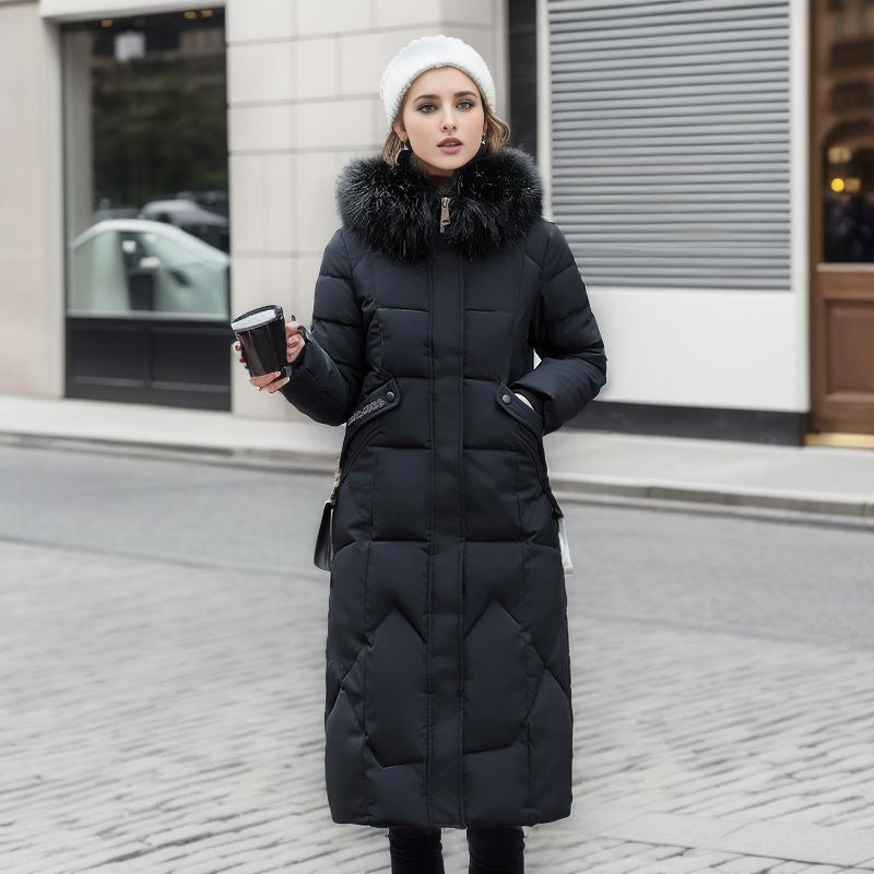 A woman wearing a black, knee-length, quilted puffer coat with a large black fur hood.