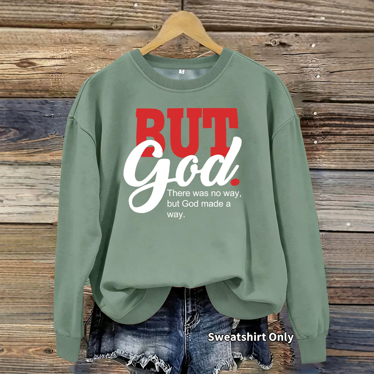 Sage green cotton crewneck sweatshirt with red and white "BUT God" text.