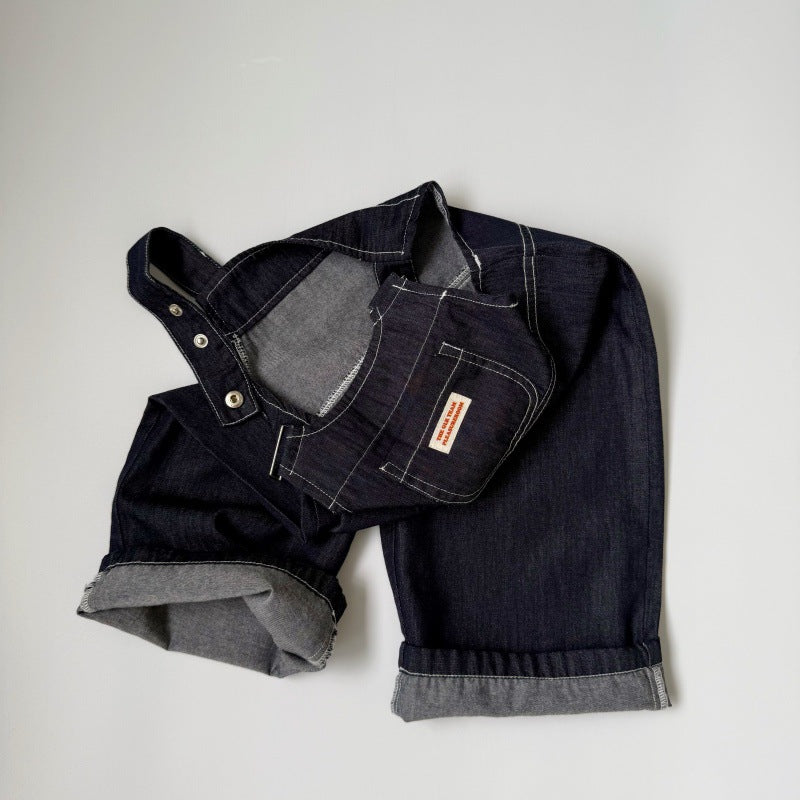 Dark denim overalls with contrast stitching, cuffed hems, metal snap buttons, and a small front pocket label.