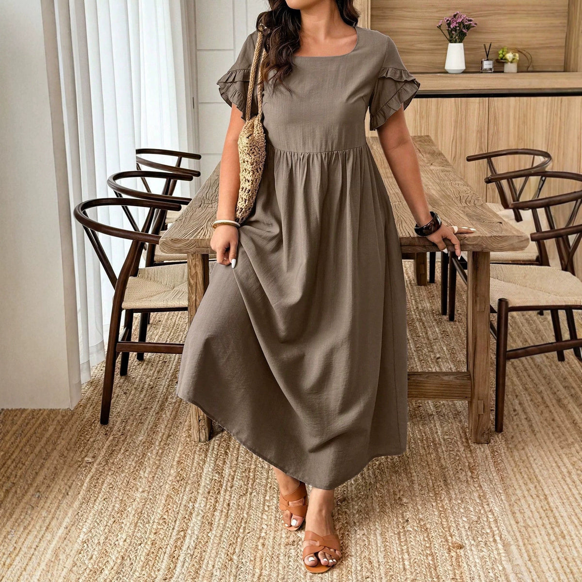 Taupe midi dress with a square neckline, ruffled sleeves, and gathered waist, styled with a straw bag.