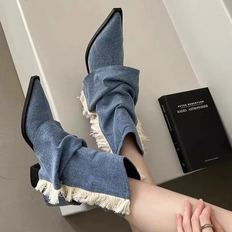 Blue denim pointed-toe mid-heel boots with slouchy shafts and white fringe trim.