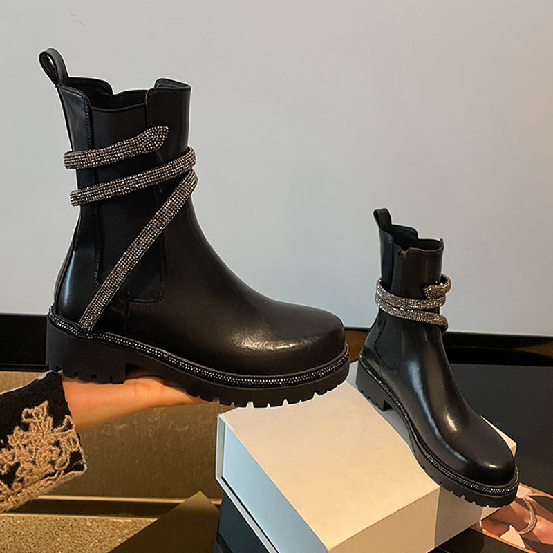 Black leather ankle boots with chunky lug soles and wrapped rhinestone snake straps.