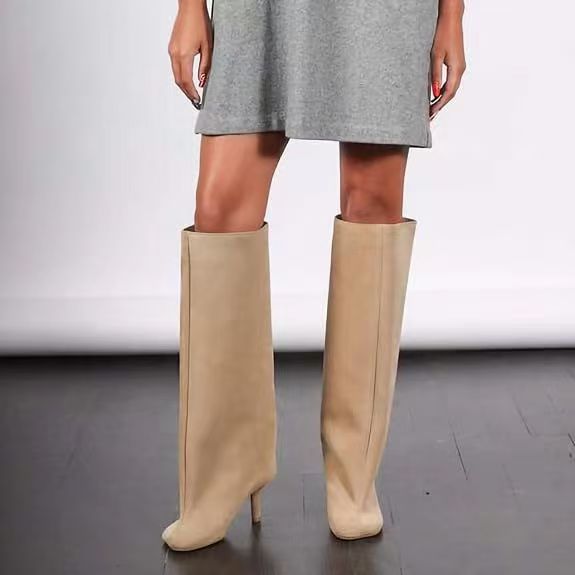 Beige knee-high faux leather boots featuring a wide, structured shaft with a front seam and a stiletto heel.