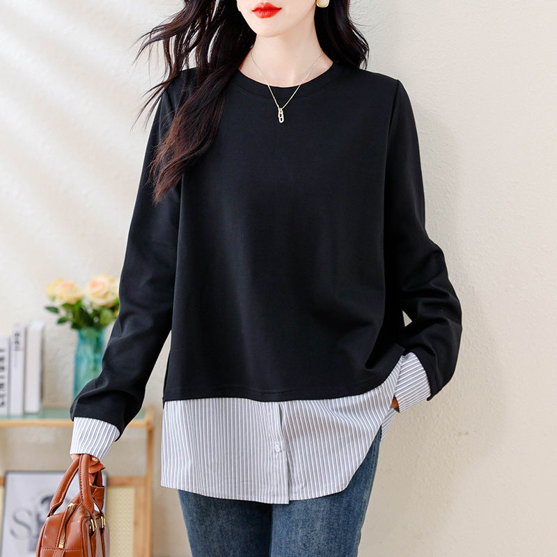 A casual black crewneck top with a layered white striped shirt hem and cuffs.