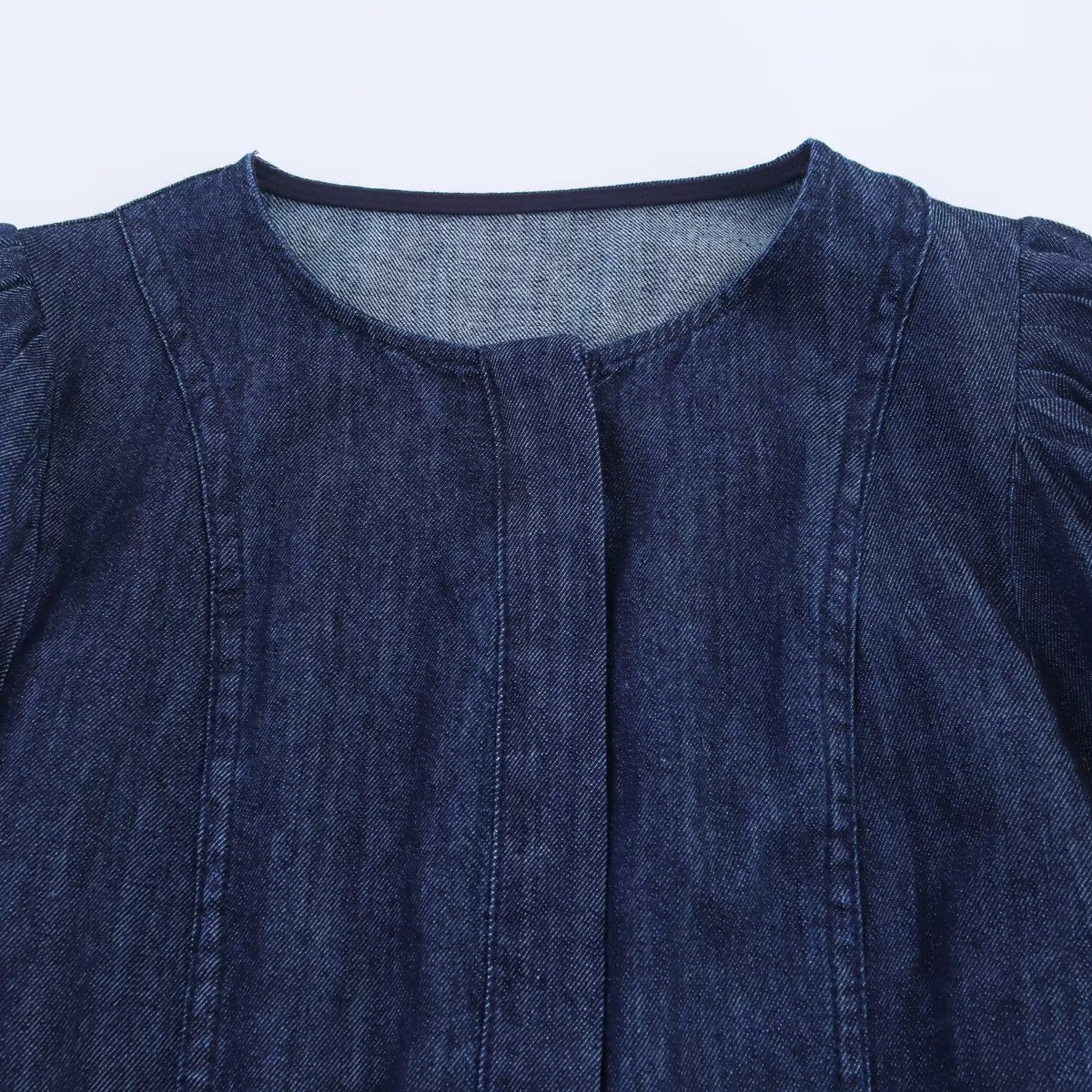 Dark blue denim jacket with round neckline, hidden button placket, and seam details on chest.