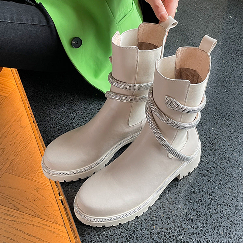 Beige leather ankle boots with chunky lug soles and wrapped rhinestone straps.