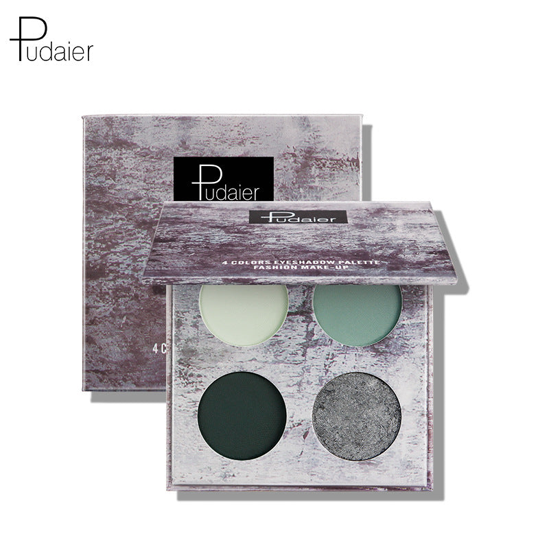 Purple cardboard eyeshadow palette with marble pattern and four green and grey shades in front of its matching box.