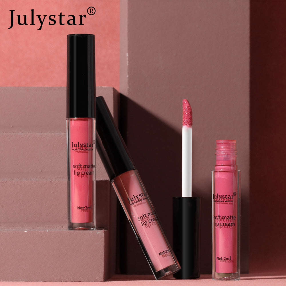 Julystar soft matte pink lip cream in transparent plastic tubes with black caps on a pink pedestal.