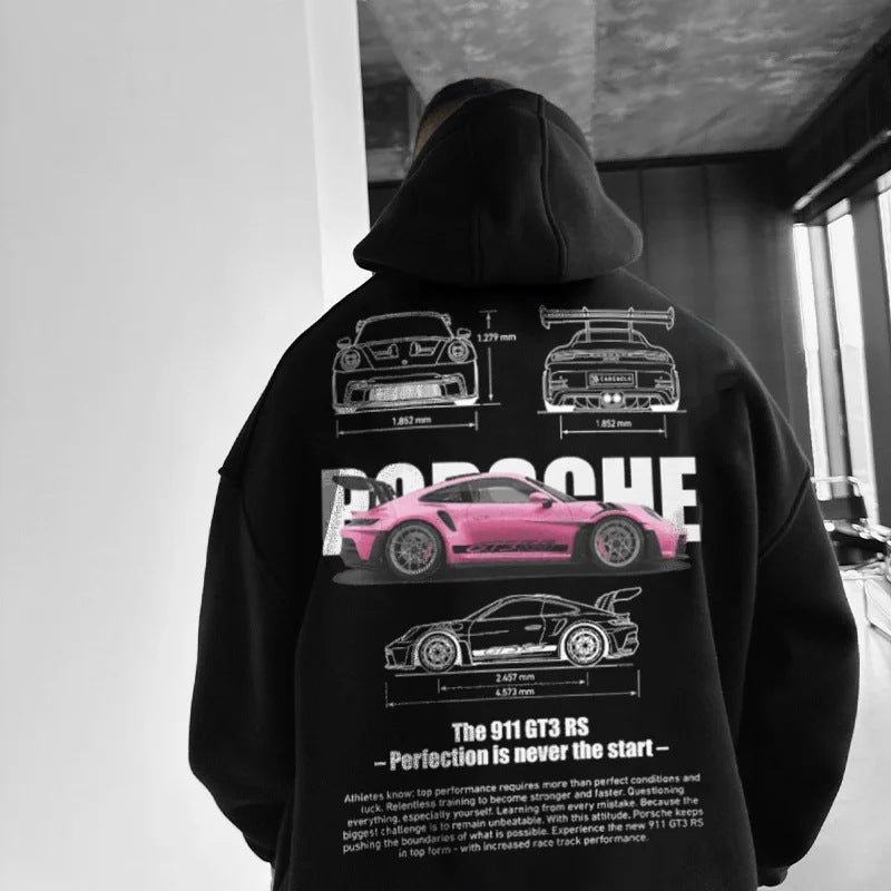 A person wears a black hoodie featuring a large back graphic of a pink Porsche and white technical car sketches.