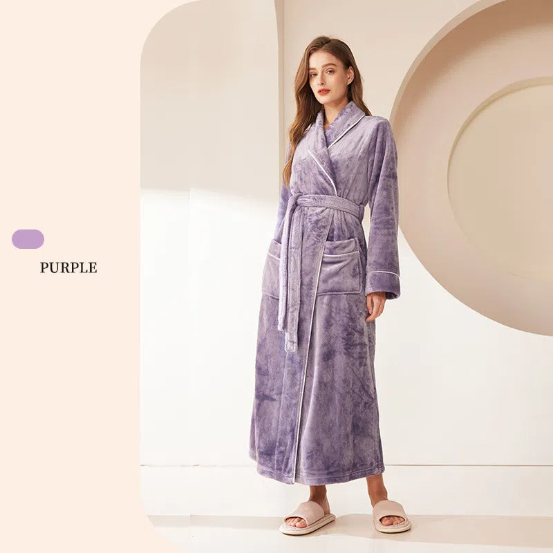 A woman wearing a purple fleece bathrobe with a tie belt, shawl collar, and white piping details.