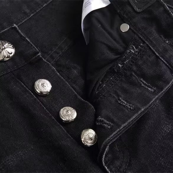 Black denim jeans with ornate silver metal button fly and floral embossing.