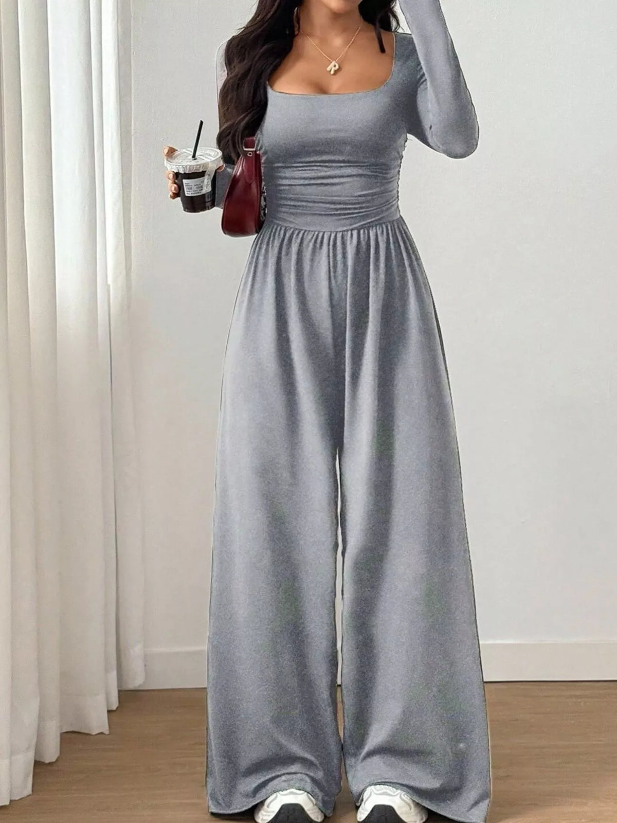 Trendsi ruched square neck wide-leg jumpsuit displayed on a model, featuring a fitted bodice and flowing wide-leg pants.