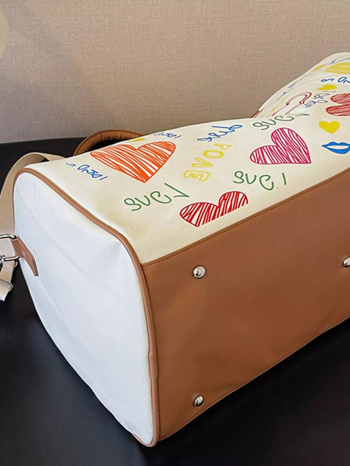 Printed duffel bag with adjustable strap from Plush Fashion Hub, showing colorful design and sturdy handle for travel or gym use.
