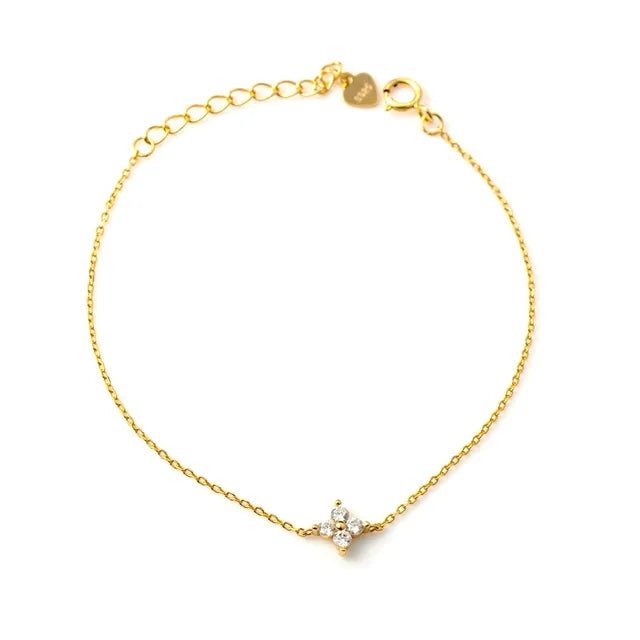 Gold chain bracelet with a four-stone crystal clover pendant and a clasp extension.