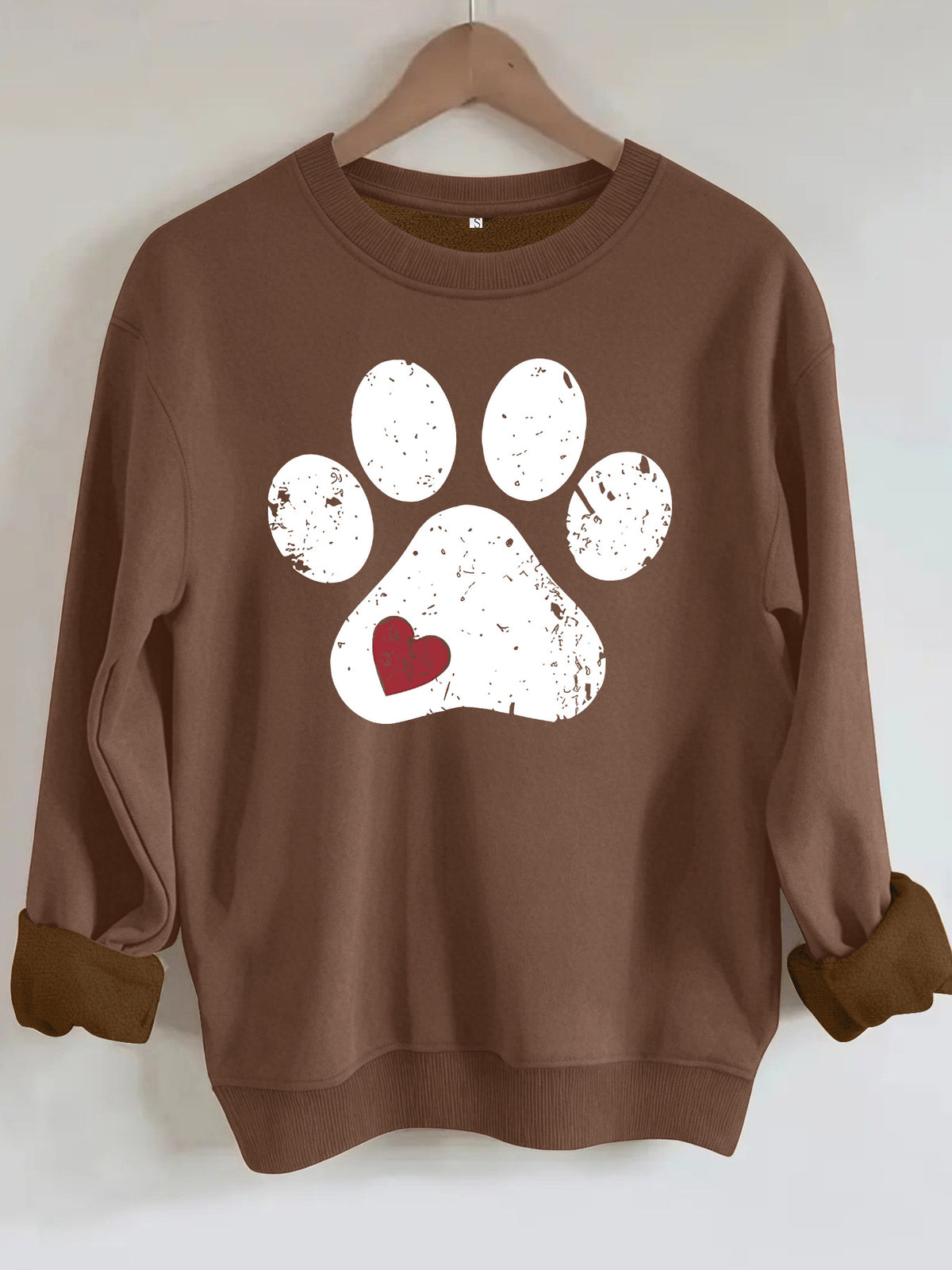Brown crewneck sweatshirt featuring a distressed white paw print with a small red heart.