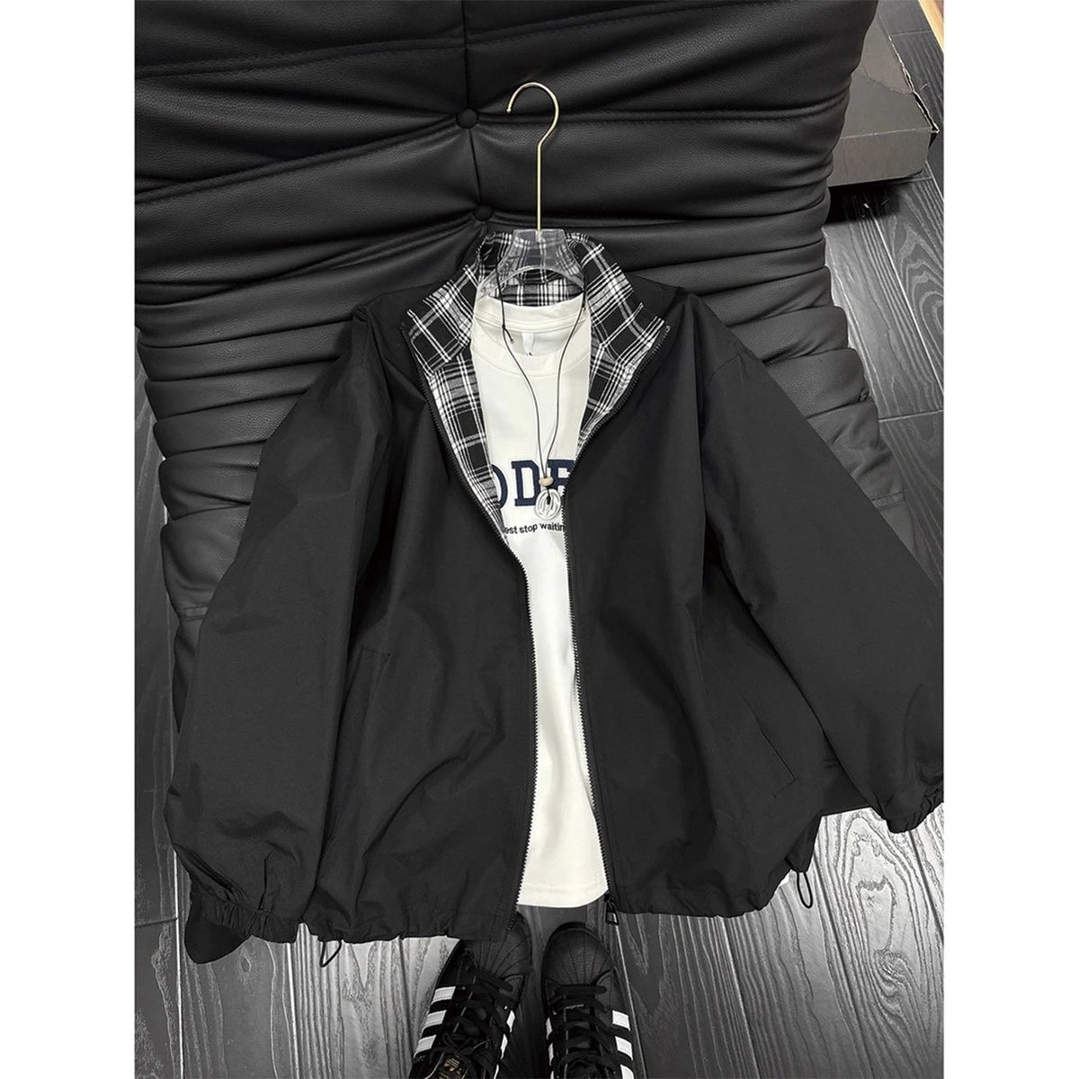 Black zip-up jacket with plaid collar and cuffs, layered over a white t-shirt.