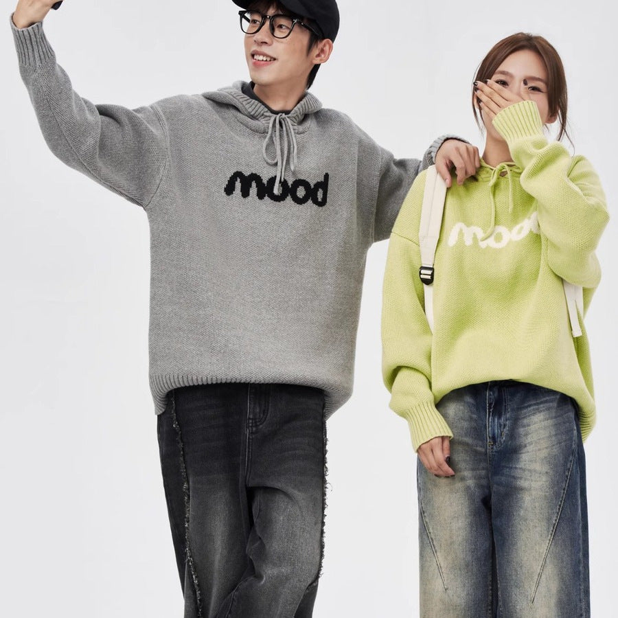 A man and woman wearing matching gray and lime green knit hooded sweaters with "mood" text across the chest.