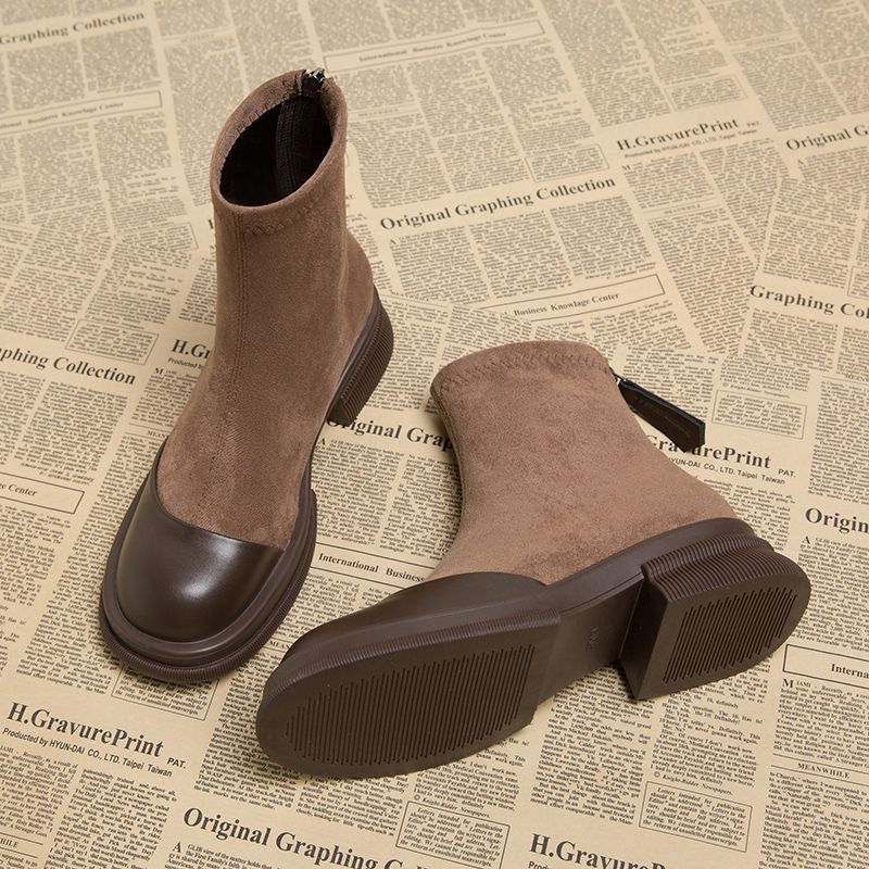 Brown suede ankle boot with round toe cap, low block heel, and back zipper on newspaper print background.