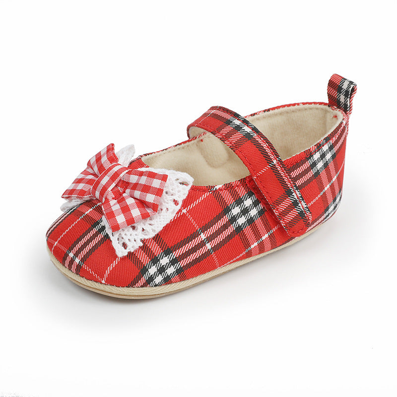 Red plaid fabric baby shoe with white lace-trimmed bow and hook-and-loop strap.