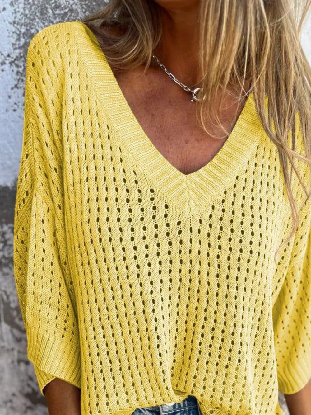 Yellow V-neck knit sweater with an open-weave pattern and ribbed trim worn by a person.