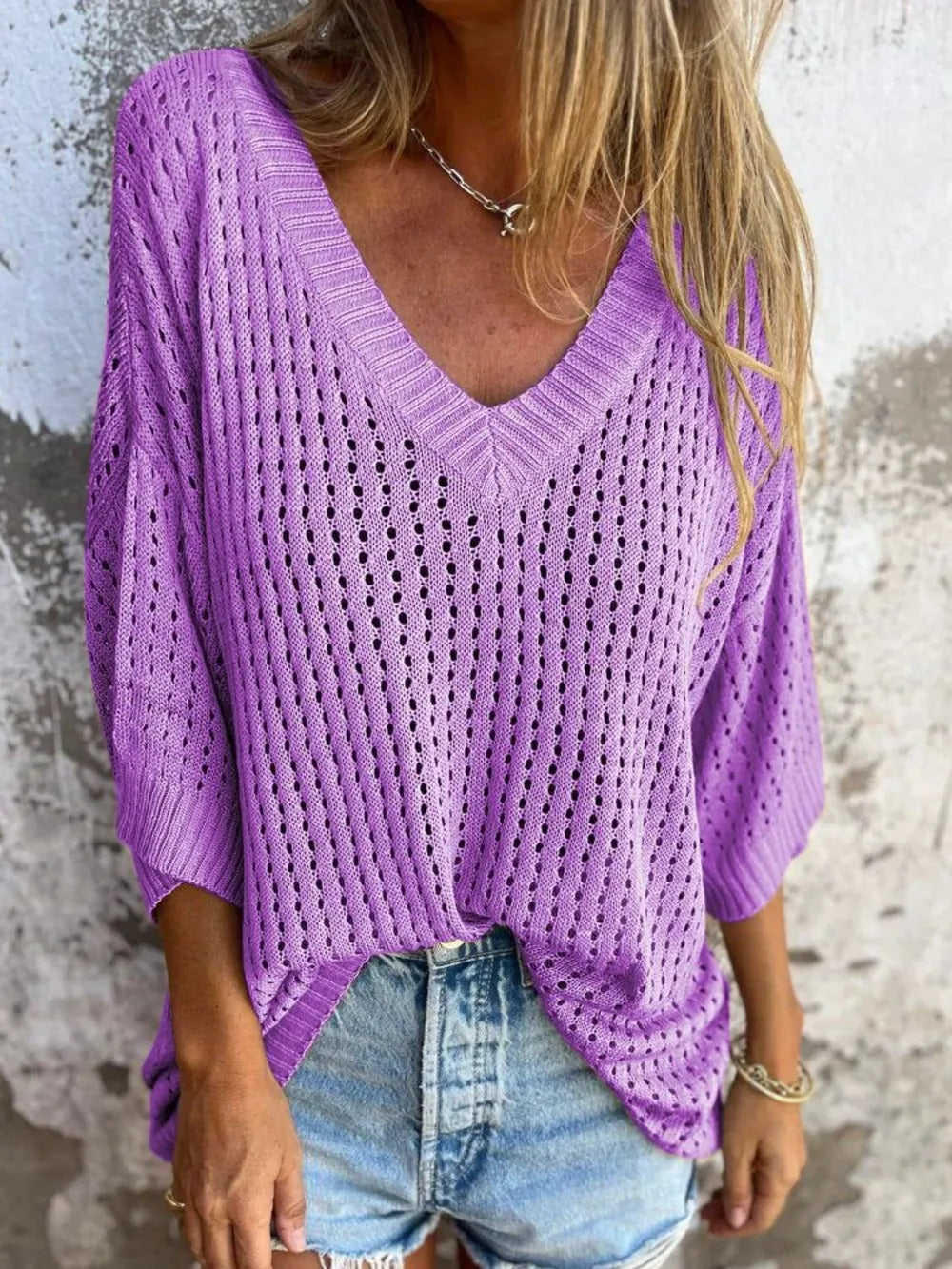 Purple knit V-neck sweater with an open-stitch pattern and half sleeves, worn over denim shorts.
