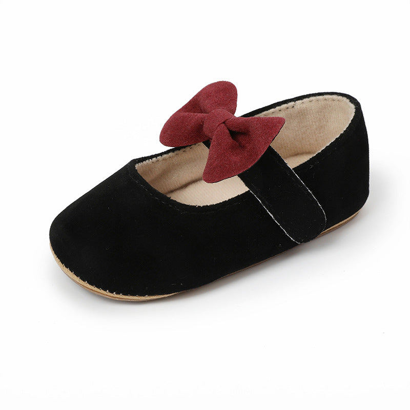 Black suede baby Mary Jane shoe with a maroon bow on the strap.