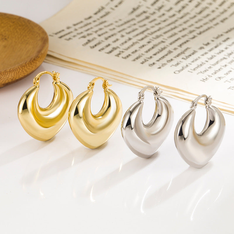 Two pairs of thick, teardrop-shaped hoop earrings, one gold and one silver, with a polished finish and hinged clasps.
