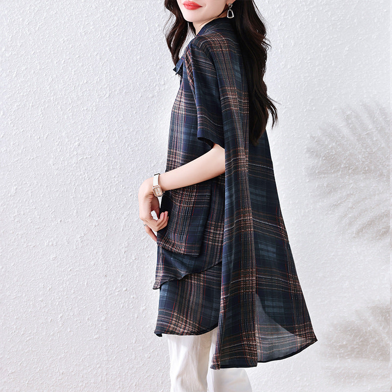 Side view of a woman wearing a blue plaid chiffon tunic with short sleeves and a draped asymmetrical hem.