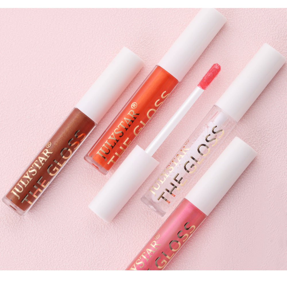 Four lip gloss tubes in brown, orange, clear, and pink with white caps and gold text on a pink background.