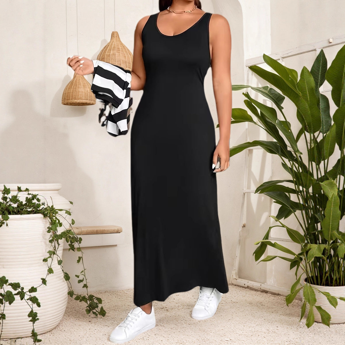 Black sleeveless maxi dress with a scoop neck, solid pattern, smooth fabric, paired with white sneakers.