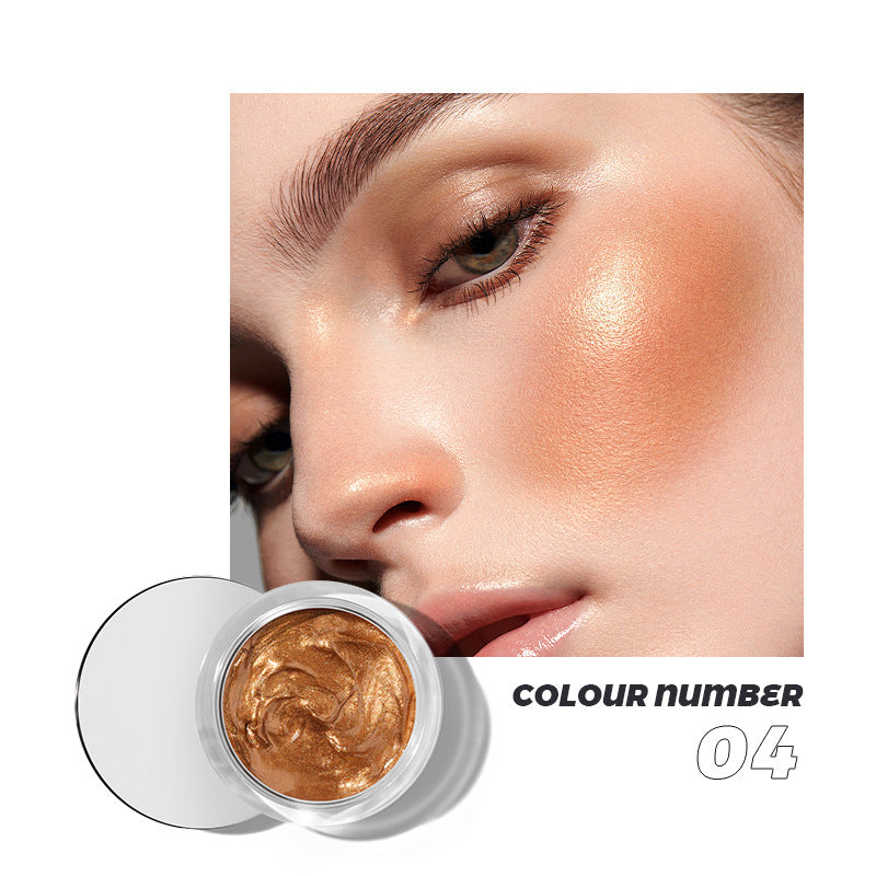 Metallic gold gel makeup in a clear jar, with a woman wearing the shimmering bronze highlighter on her cheekbone.