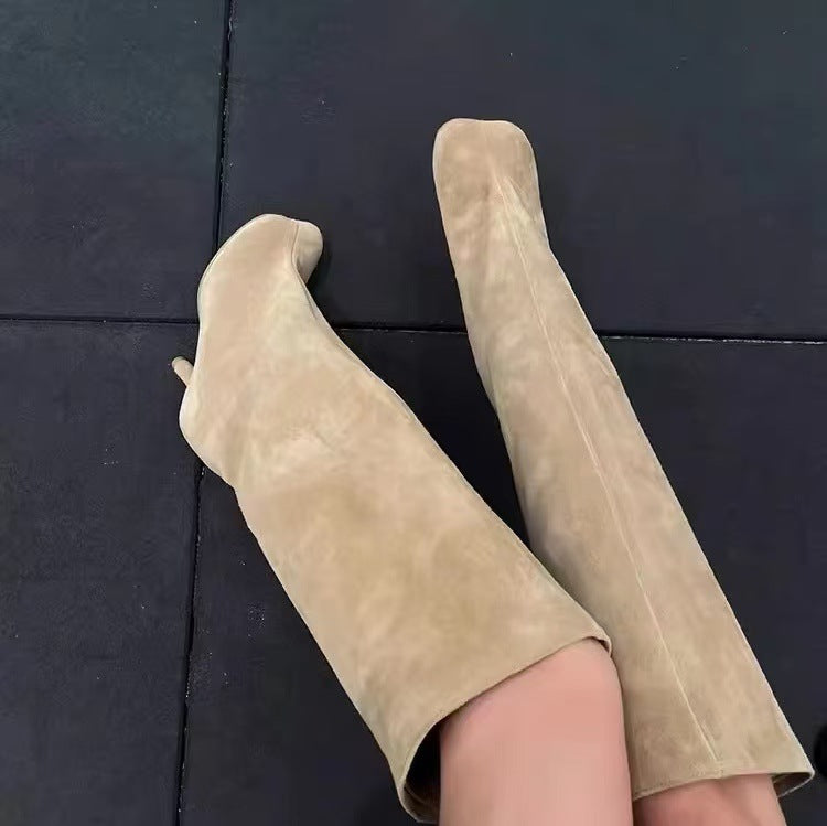Beige suede knee-high boots with thin stiletto heels and pointed toes.