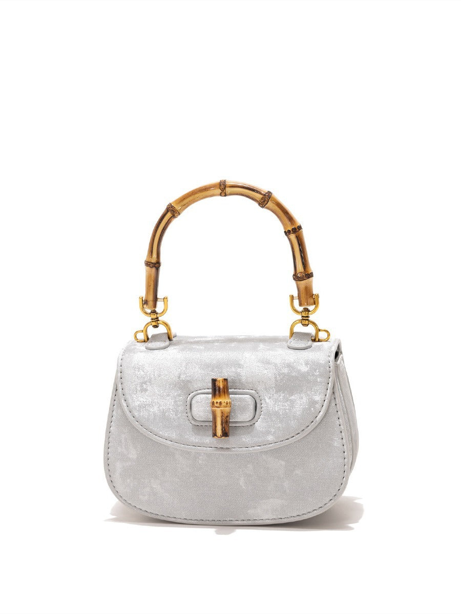 Silver velvet handbag with a bamboo top handle and bamboo turn-lock closure, featuring gold-tone hardware.