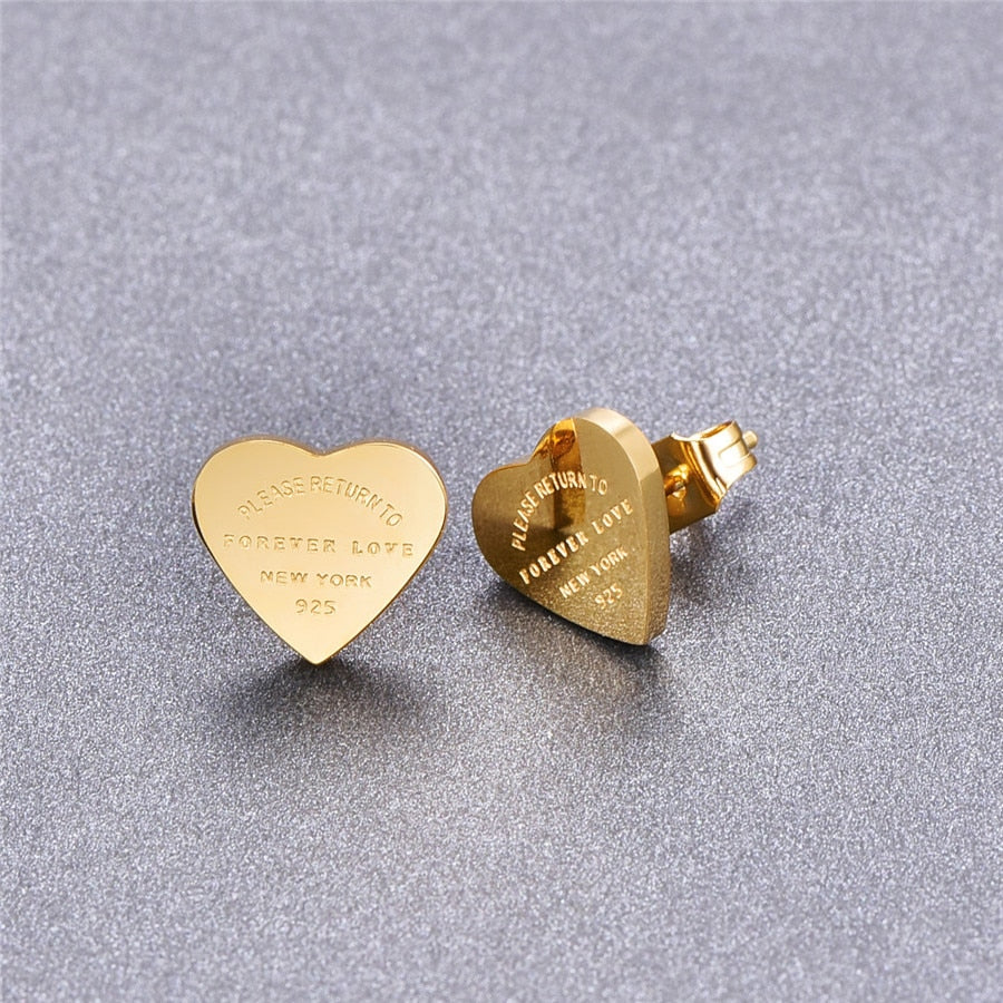 Gold-colored heart-shaped stud earrings engraved with “Please Return To Forever Love New York 925.”