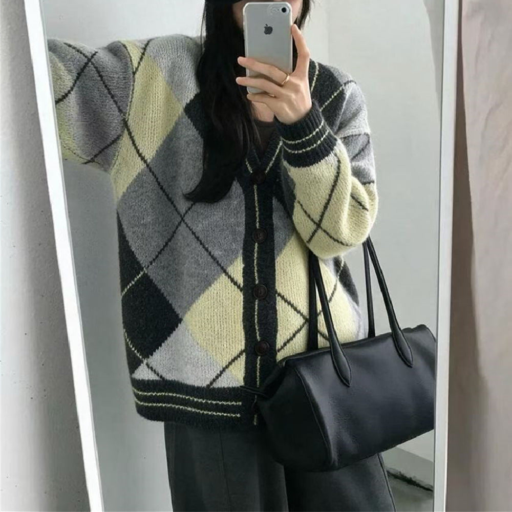 A person wears a V-neck cardigan featuring a yellow, grey, and black argyle pattern and dark buttons.