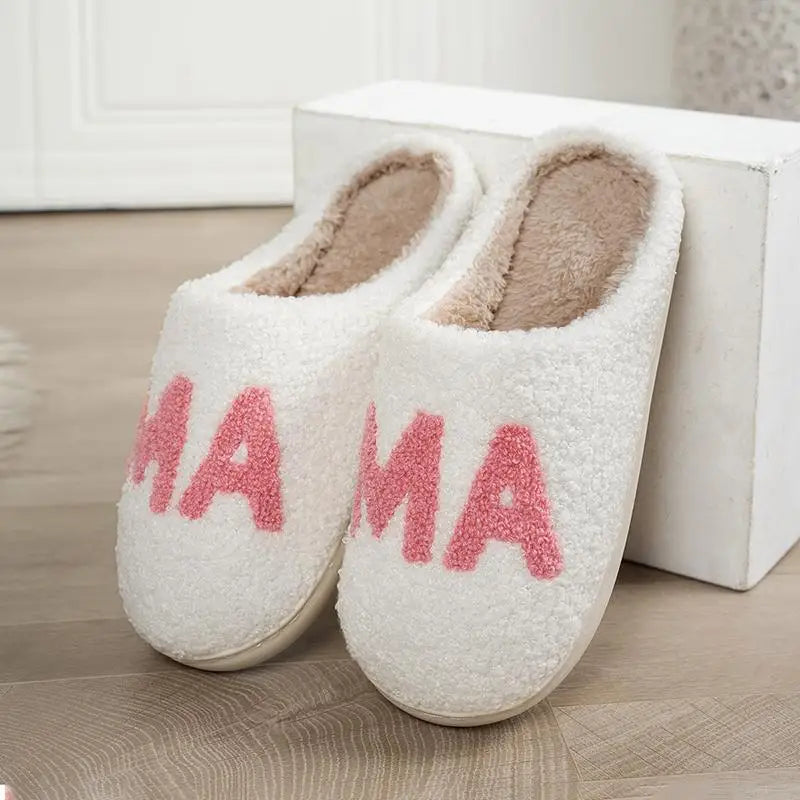 White fuzzy slippers with brown lining and pink "MAMA" text on the side.