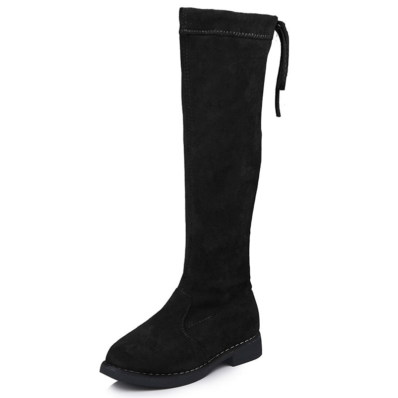 Black suede over-the-knee boot with flat sole, round toe, and back tie detail.