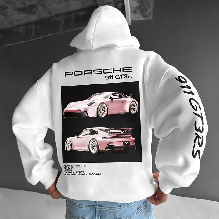 A person wears a white hoodie featuring a black-and-pink Porsche graphic on the back and text on the sleeve.