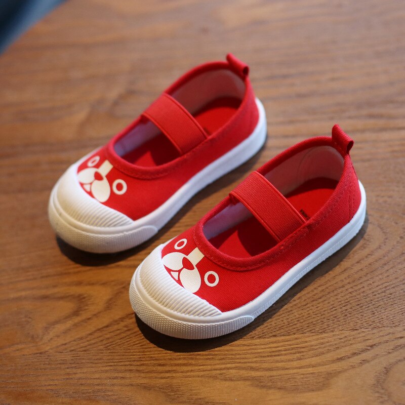 Red canvas slip-on children's shoes with white toe caps, elastic straps, and white dog face prints.