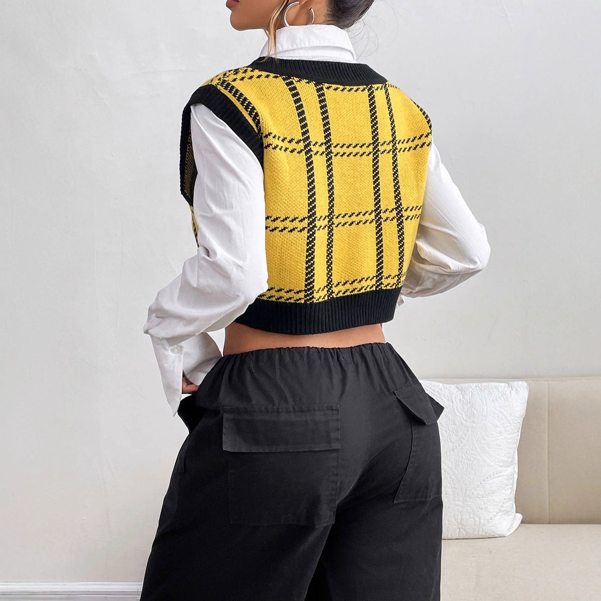 Yellow and black plaid knit sweater vest worn over a white shirt and paired with black cargo pants.