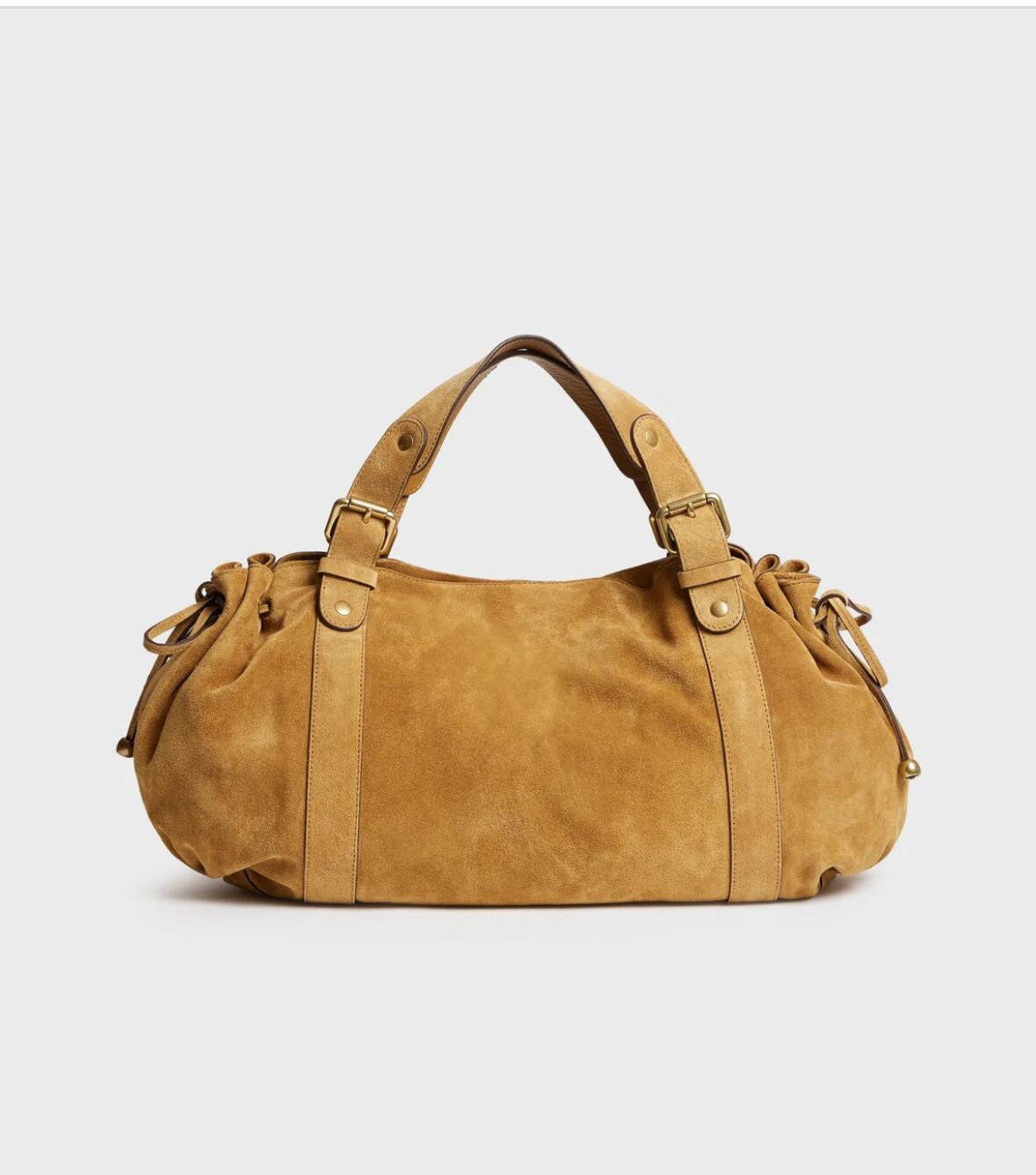 Tan suede shoulder bag with dual top handles, brass buckles, vertical straps, and cinched sides.