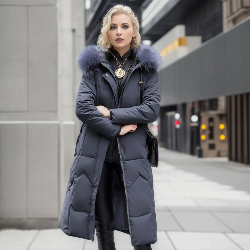 A woman wears a long, dark grey padded winter coat with a large fluffy hood.