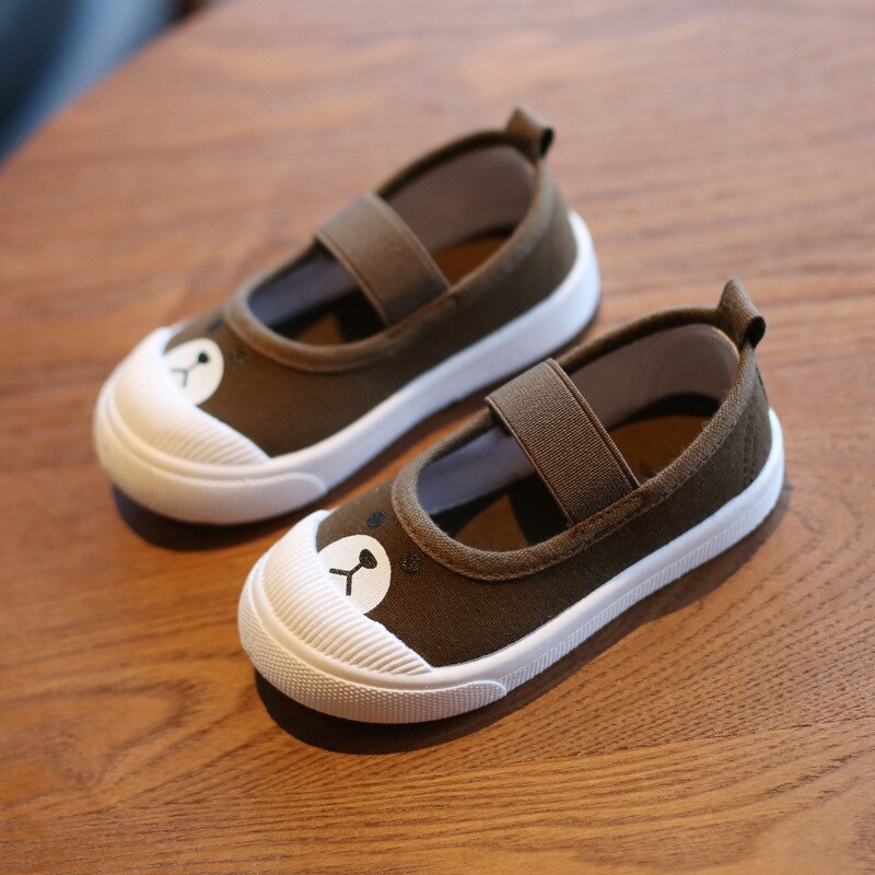 Brown canvas children's shoes with white soles, elastic straps, and cute bear face toes.
