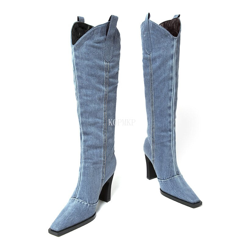 Blue denim western boots with square toes, block heels, pull tabs, and stitched seam details.