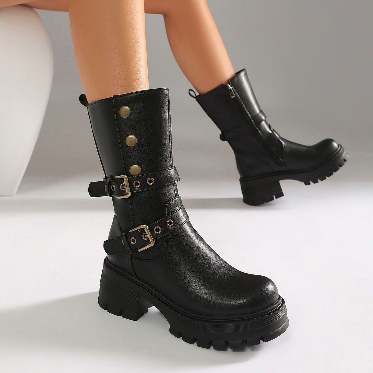 Black leather platform boots featuring side buckles, metal eyelets, and stud details on a chunky heel.