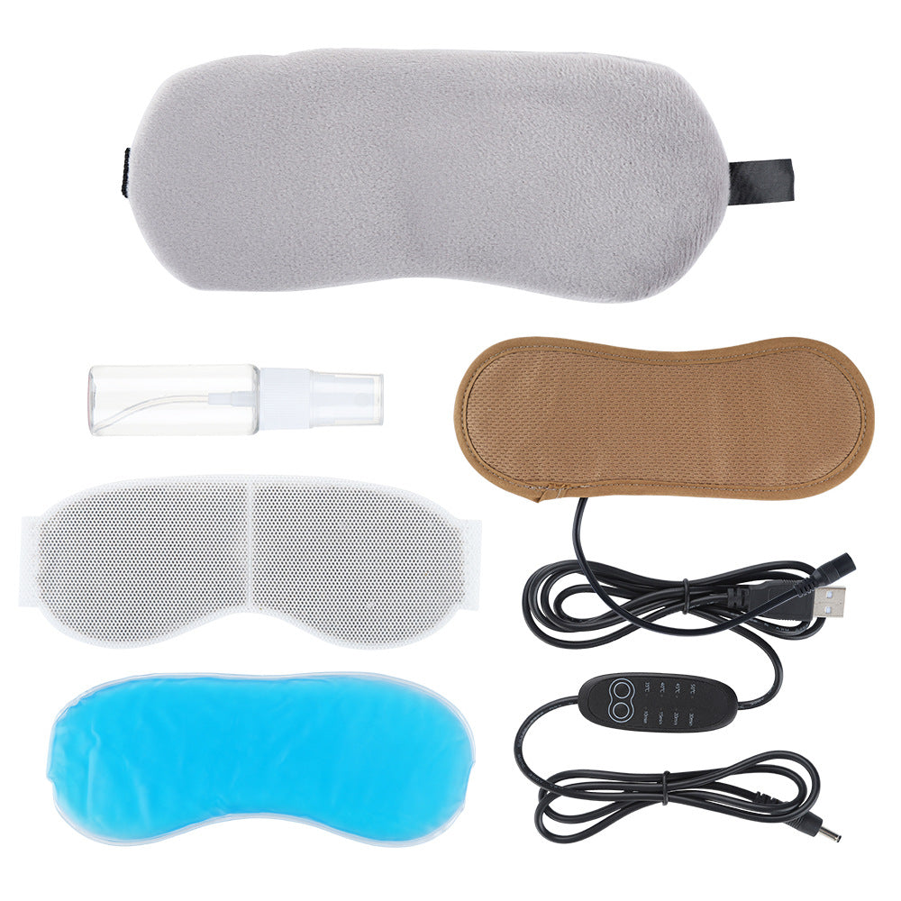 Grey plush sleep mask set with brown heated insert, white mesh insert, blue gel pack, spray bottle, and USB controller.
