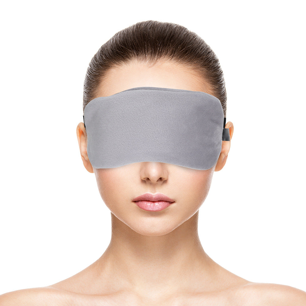A person wearing a solid gray, fleece sleep mask.