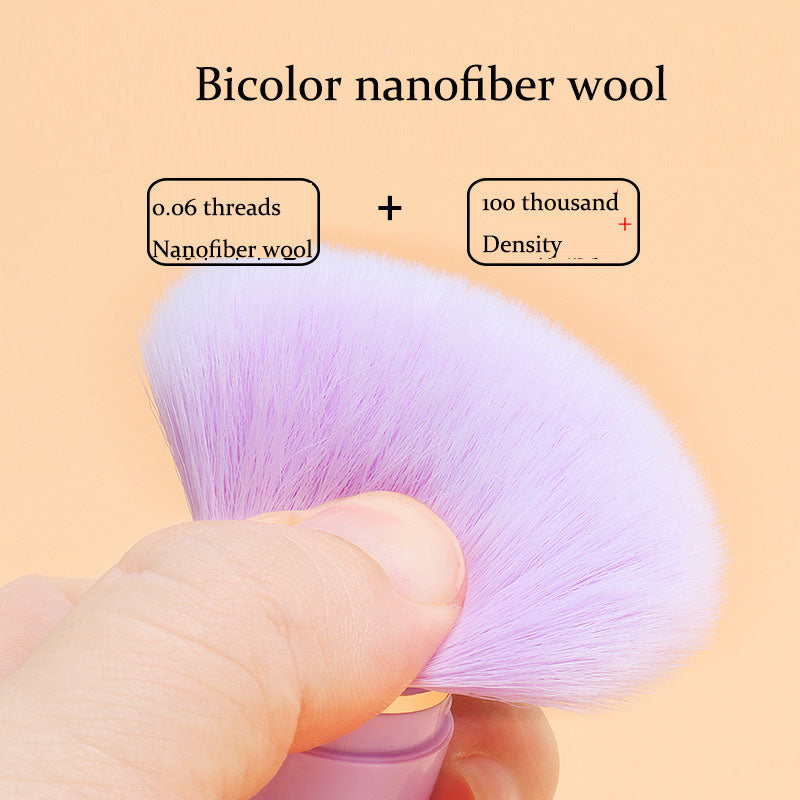Soft, purple nanofiber wool makeup brush with a dense, bicolor bristle head held against an orange background.